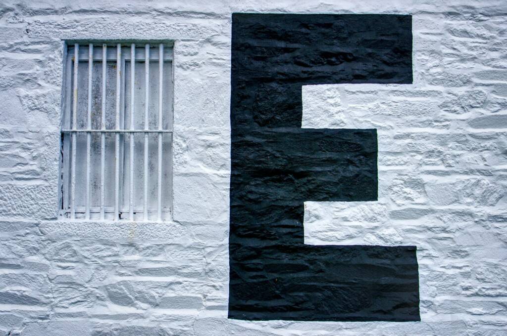 sur un mur blanc une lettre e majuscule en noir