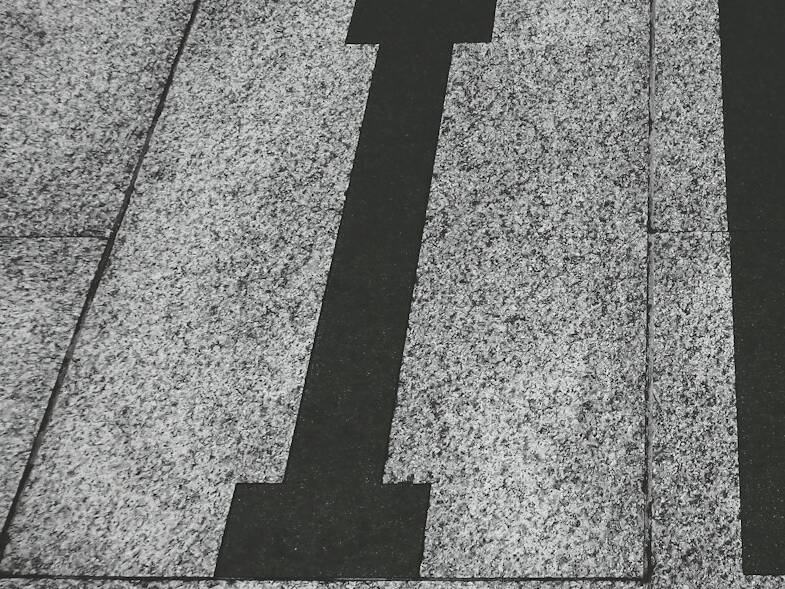 lettre i noire sur fond pavé gris