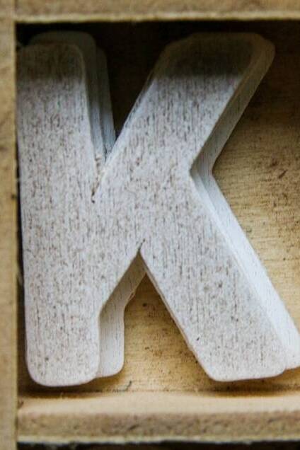 Lettre K blanche sur un cadre en bois clair